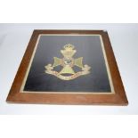 A framed and glazed woolwork embroidery of the badge of the 12th County of London Regiment The