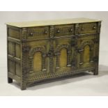 A 20th century Jacobean Revival oak sideboard with carved decoration, fitted with three drawers