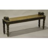 A late Victorian carved oak window seat with lion handrests, on barley twist legs, height 55cm,