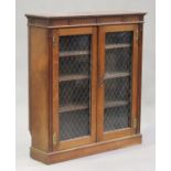 An Edwardian oak glazed bookcase, the fluted and carved rosette frieze above a pair of doors inset