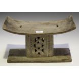 An Ashanti carved wooden stool, the curved seat raised on a pierced support and rectangular base,