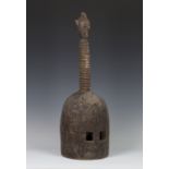 A Senufo carved hardwood helmet mask of domed form, Ivory Coast, the ribbed pole finial topped