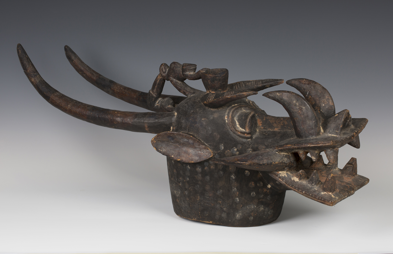 A Senufo Kponyungo carved and painted helmet mask, Ivory Coast, modelled typically in the form of