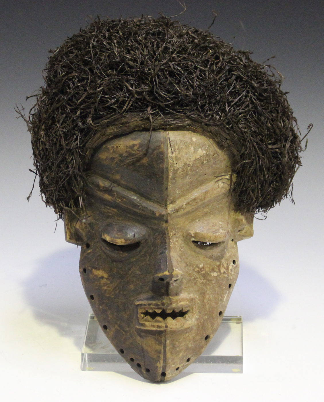 An African carved hardwood mask with painted surface and applied grass hair, possibly Xhosa, South