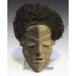 An African carved hardwood mask with painted surface and applied grass hair, possibly Xhosa, South