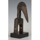 A Senufo carved hardwood heddle pulley, Ivory Coast, the finial modelled as the head of a hornbill