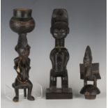 An African carved wooden figure of a seated female, modelled with a vessel on her head, height 30cm,