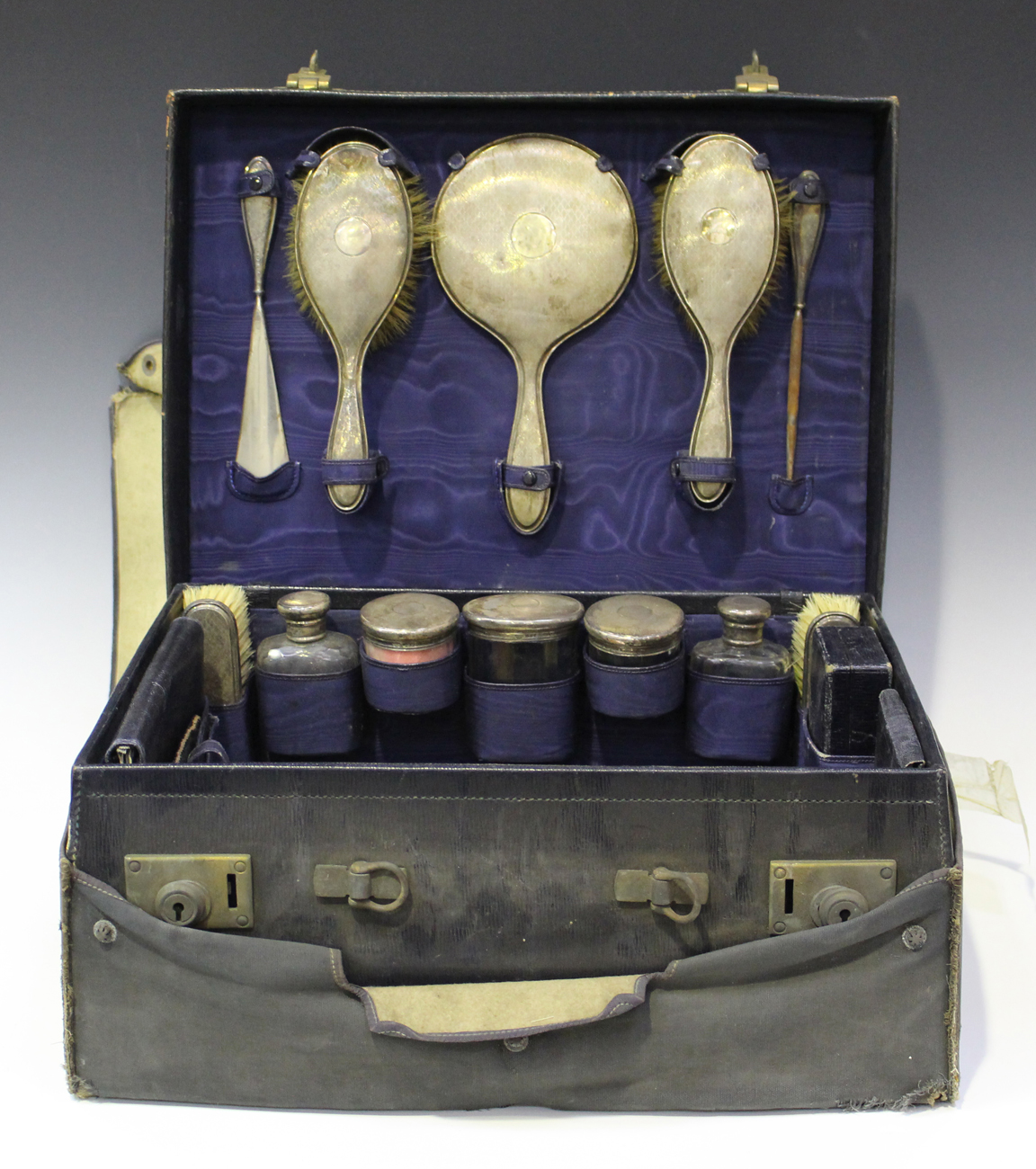 A George V leather travelling vanity case, the interior containing a selection of silver mounted