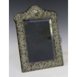 A late Victorian silver shaped rectangular dressing table mirror with pierced and embossed