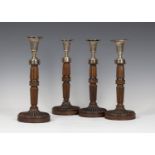 A set of four George III and later silver and mahogany candlesticks, each silver reeded urn shaped