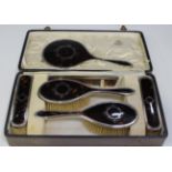 A George V silver and tortoiseshell dressing table set, comprising two clothes brushes, two