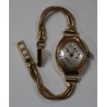 A gold oval cased lady's wristwatch, the lozenge shaped silvered dial with Roman numerals, on a gilt