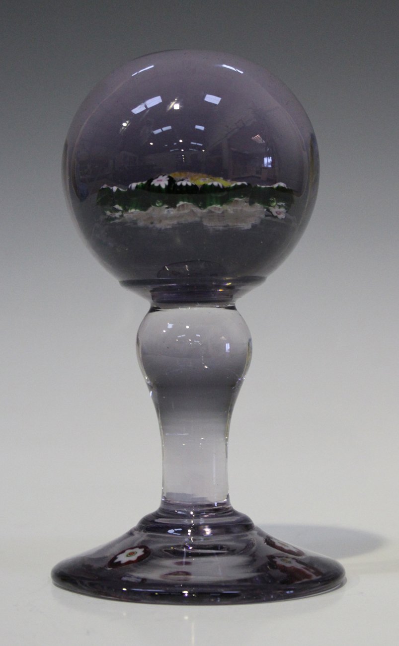 A purple tinted glass paperweight wig stand, late 19th/early 20th century, the spherical ball