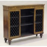 A Regency rosewood bookcase cabinet, the central open shelves flanked by two doors inset with gilt