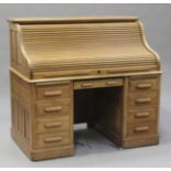 An early 20th century pale oak roll-top desk, the tambour front revealing pigeonholes and drawers