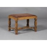 An early 20th century Arts and Crafts oak stool, the tooled brown leather drop-in seat raised on