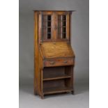 An Edwardian Arts and Crafts oak student's bureau bookcase, the canopy pediment above a pair of