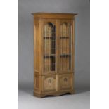 An Edwardian Arts and Crafts oak glazed bookcase, the moulded pediment above a pair of leaded