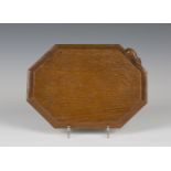 A Robert 'Mouseman' Thompson oak bread board of canted rectangular form, the shaped edge with