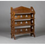 An early 20th century Arts and Crafts style walnut open bookcase, the arched gallery above four