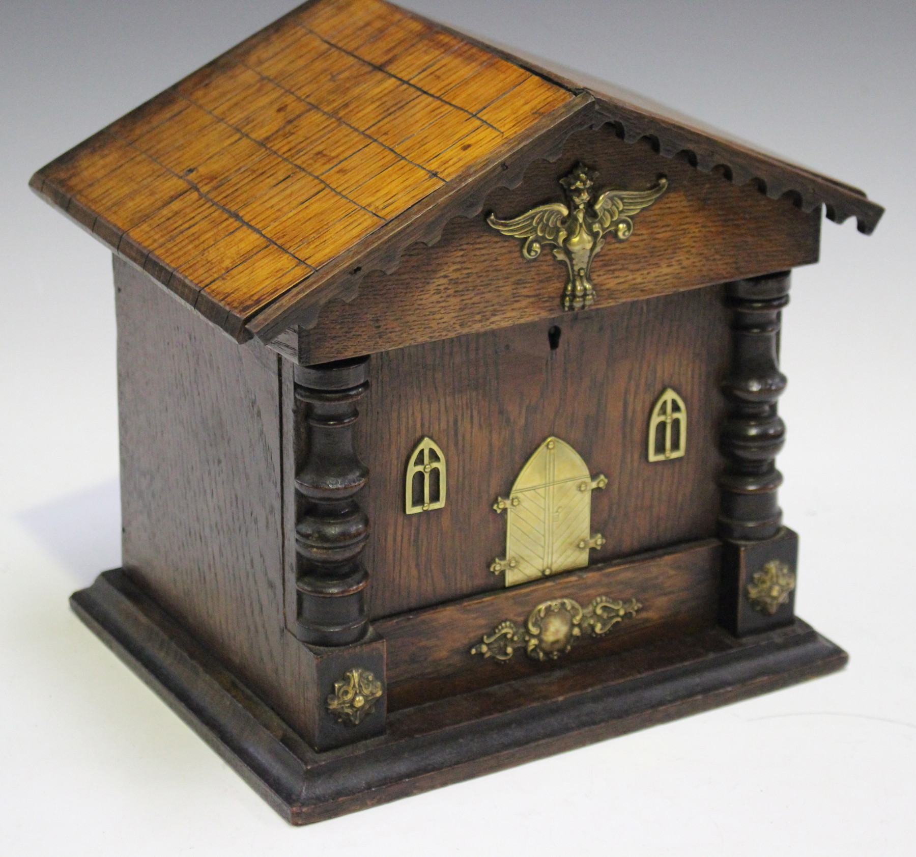 A late Victorian oak and brass mounted novelty smoker's box of architectural form, the hinged roof