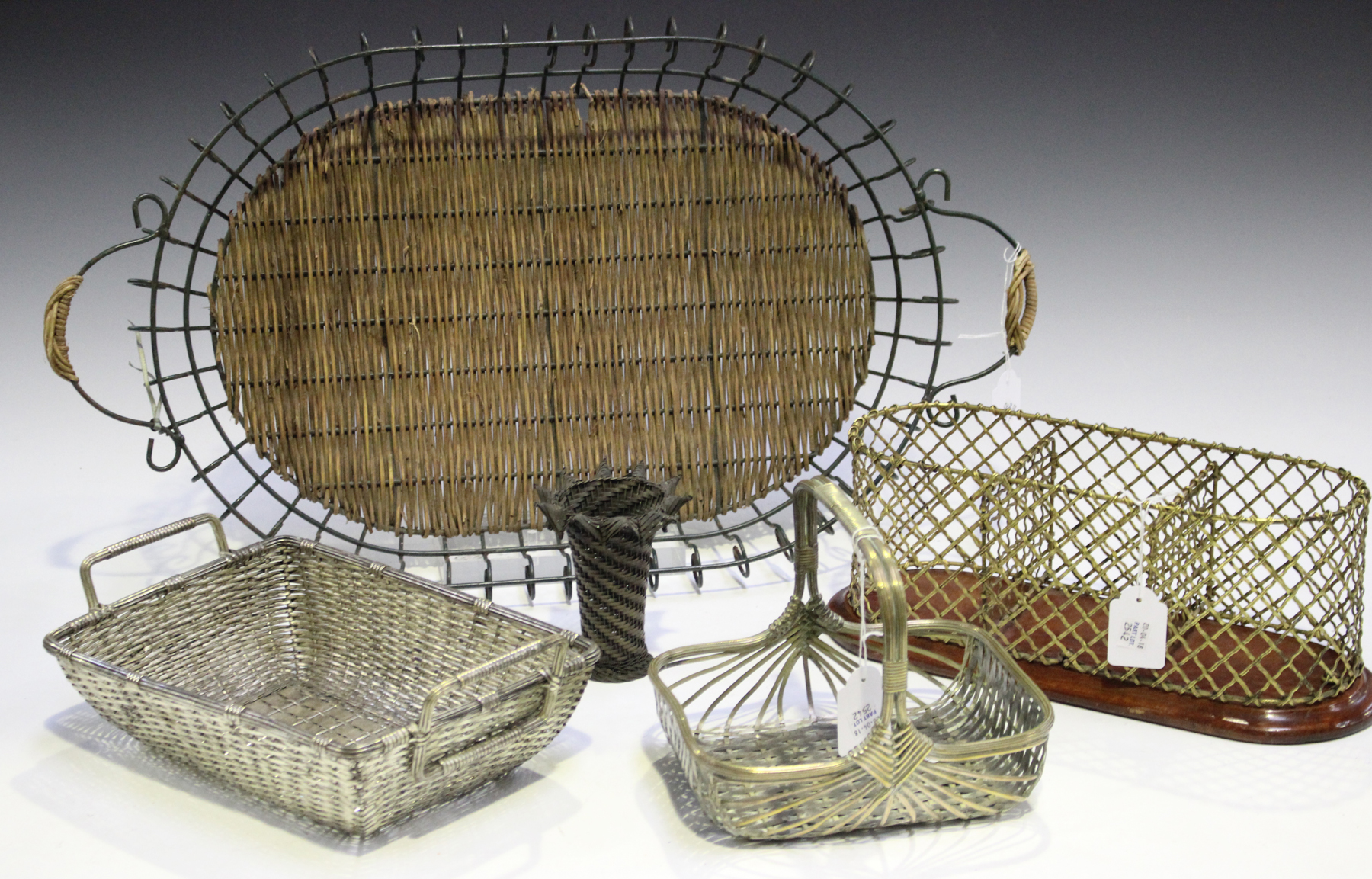 An early 20th century gilt metal wirework bottle stand, width 32cm, together with two woven metal