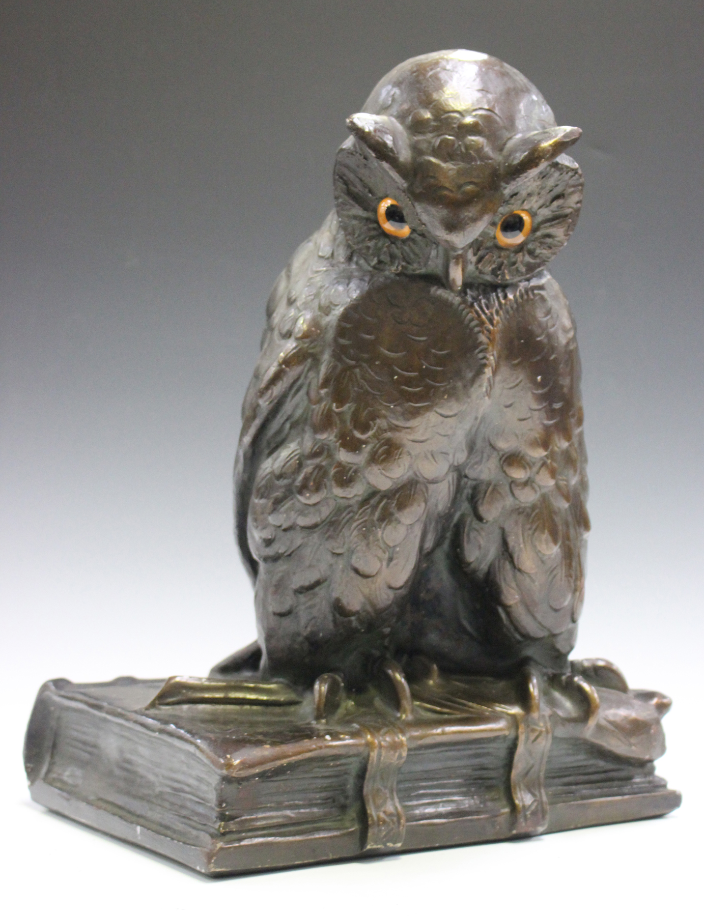 An early 20th century German bronzed cast plaster model of an owl seated on a quill and book,