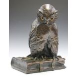 An early 20th century German bronzed cast plaster model of an owl seated on a quill and book,