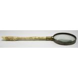 A late 19th/early 20th century brass mounted magnifying glass, the ivory handle carved in the form