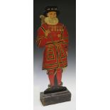 An early 20th century painted fretwork dummy board in the form of a standing beefeater, raised on