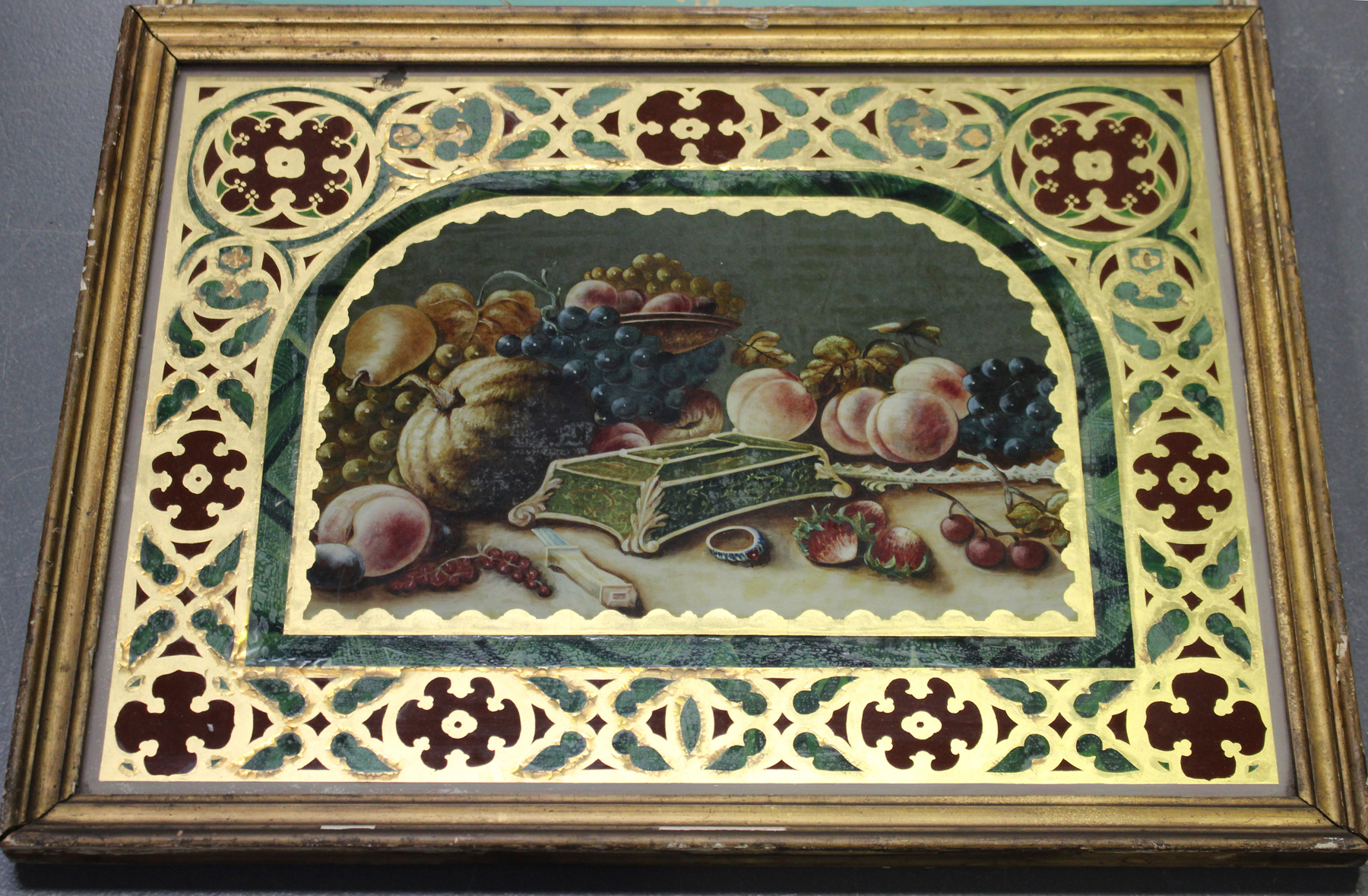 A 19th century French reverse painting on glass depicting a still life within a gilded strapwork