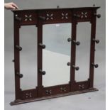 A late Victorian mahogany hanging coat rack with a central mirror panel, flanked by turned hooks,