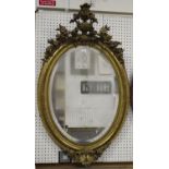 A mid-Victorian giltwood and gesso framed oval wall mirror with urn surmount, 129cm x 78cm.Buyer’s