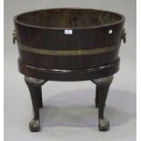 A George III mahogany and brass bound wine cooler, the coopered oval body on a later base with