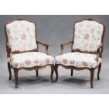 A pair of 20th century French beech framed fauteuil armchairs, the showframes with carved