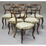 A set of six early Victorian rosewood dining chairs with carved scroll decoration, the overstuffed