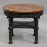 An early 20th century Continental marquetry inlaid occasional table, the pine base carved