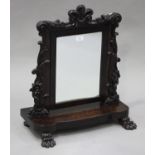 A William IV figured mahogany swing frame mirror, the carved floral crest above flowerhead and