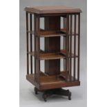 An Edwardian walnut revolving library bookcase with slatted sides, on a platform base and castors,