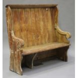 A late 19th century stripped pine settle, the panel back above downswept arms, on block end