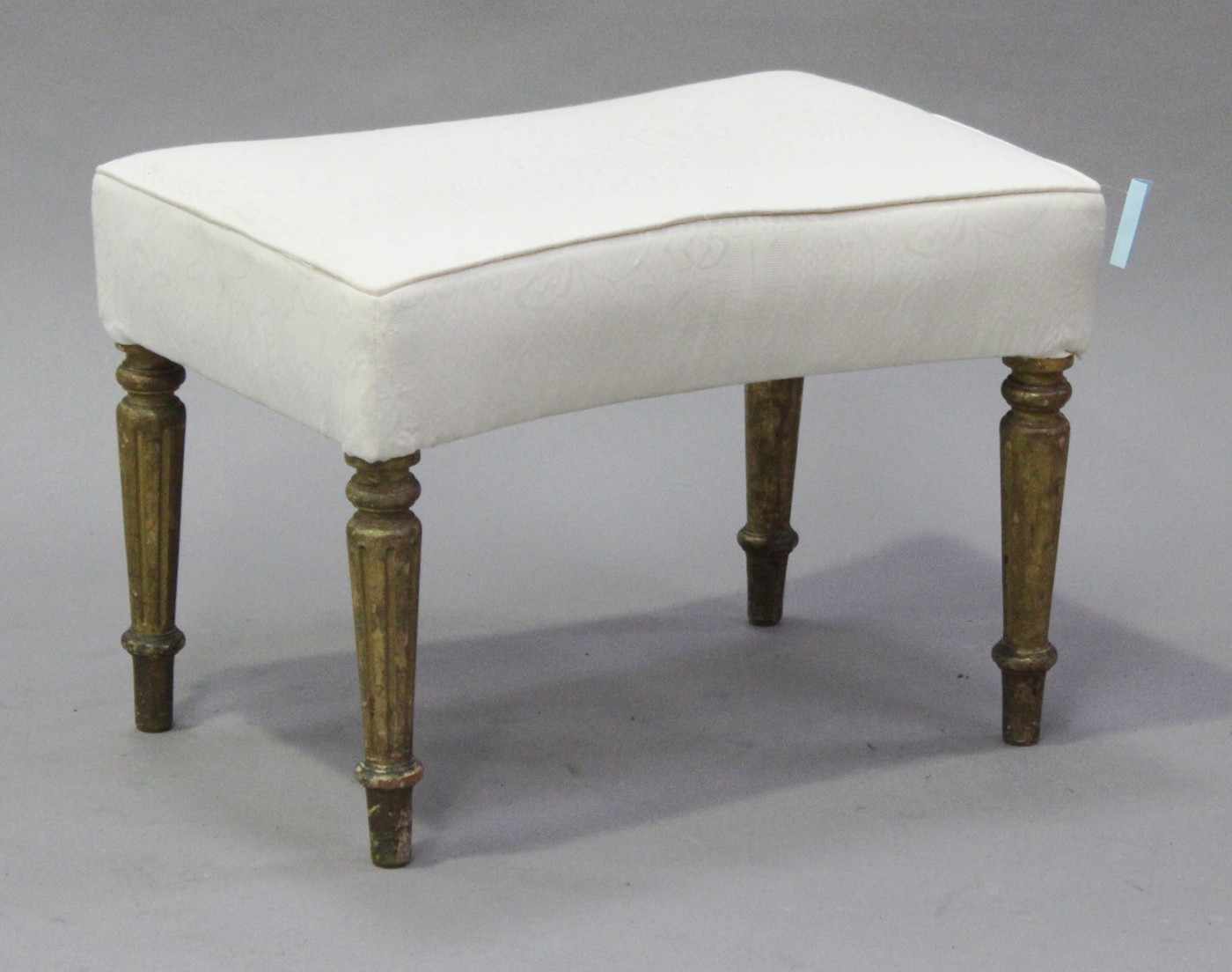 A late 19th century waisted rectangular shaped stool, the overstuffed seat on turned tapering and