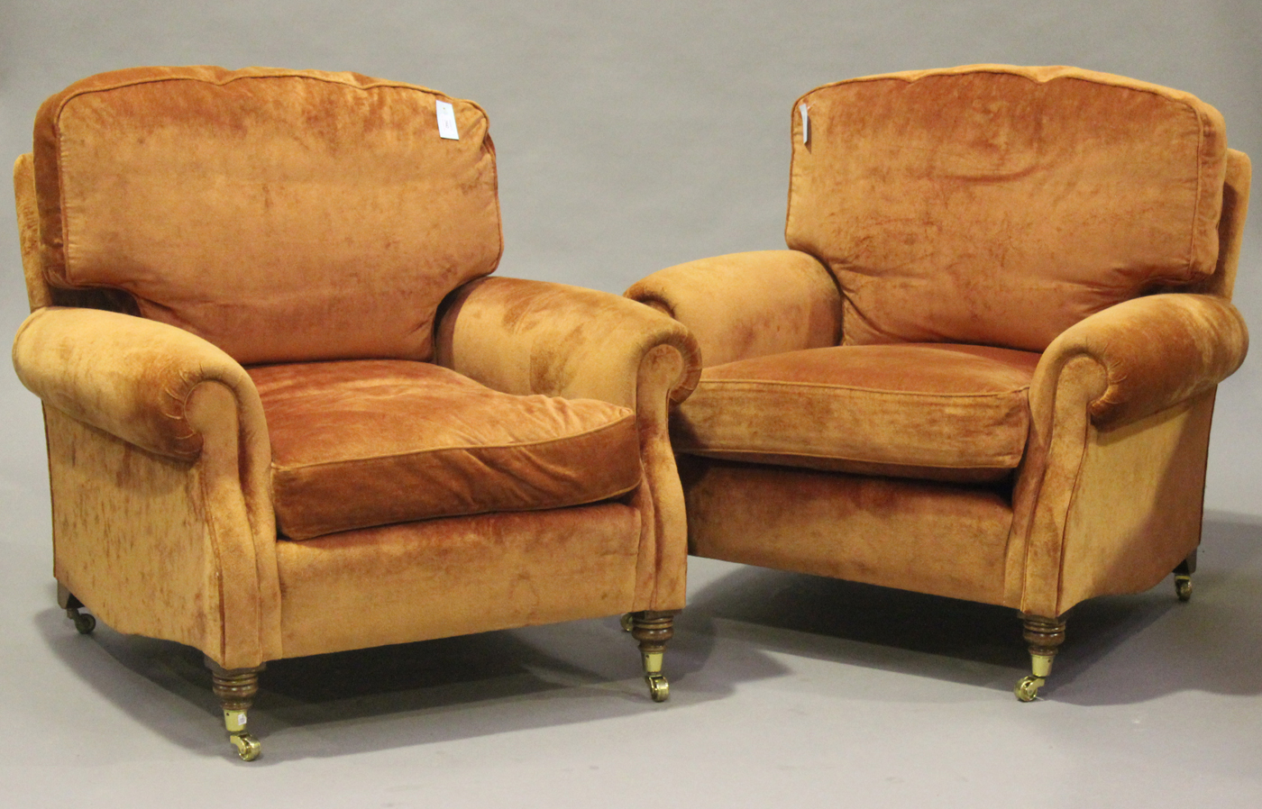 A modern three piece suite, upholstered in terracotta velour, comprising two armchairs and a three