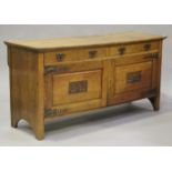 An Edwardian oak sideboard with carved decoration, fitted with two drawers above cupboards, on stile