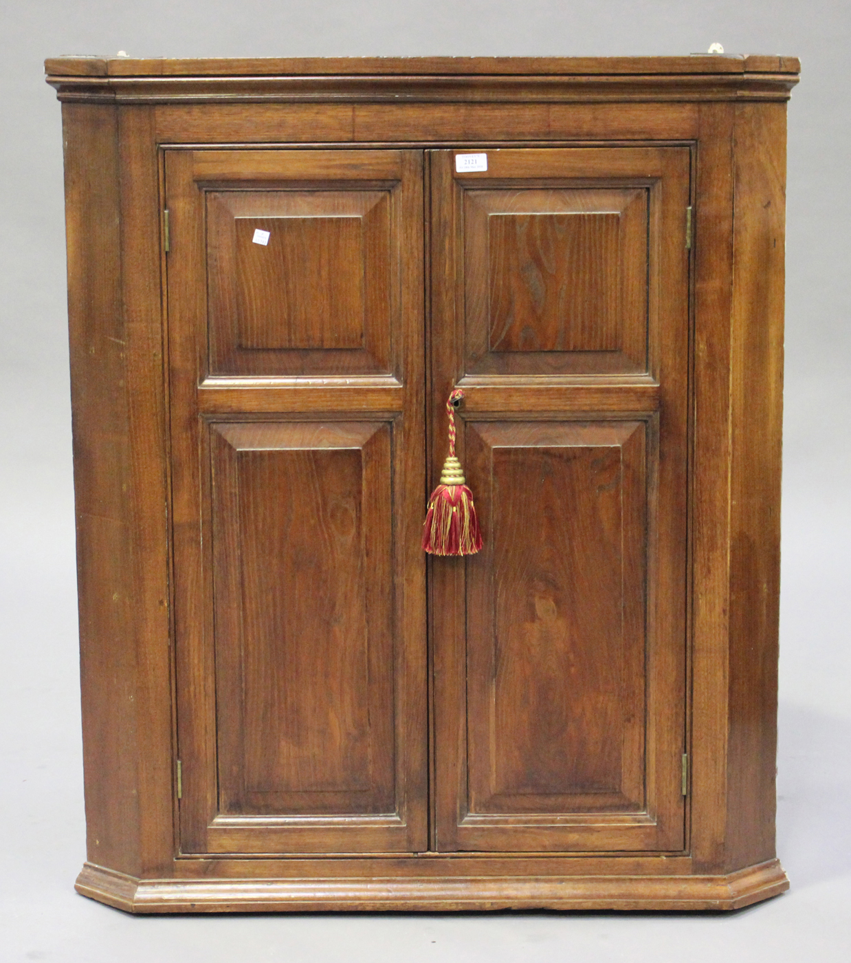 An 18th century elm and oak hanging corner cabinet, the moulded pediment above a pair of panelled