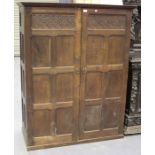 An early 20th century oak panelled cupboard with carved decoration, the moulded pediment above a