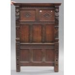 An early 20th century Carolean Revival oak single bed, the panel ends with carved decoration, on