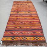 A kelhim rug, early 20th century, with overall polychrome geometric bands, 435cm x 122cm.Buyer’s