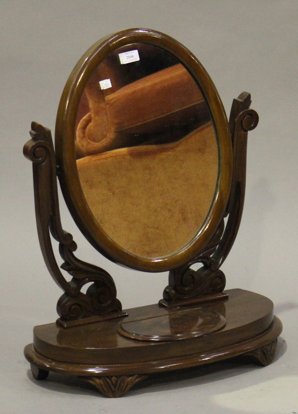 A Victorian mahogany oval swing frame dressing table mirror, raised on carved foliate supports,