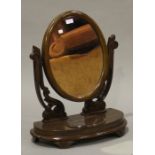 A Victorian mahogany oval swing frame dressing table mirror, raised on carved foliate supports,