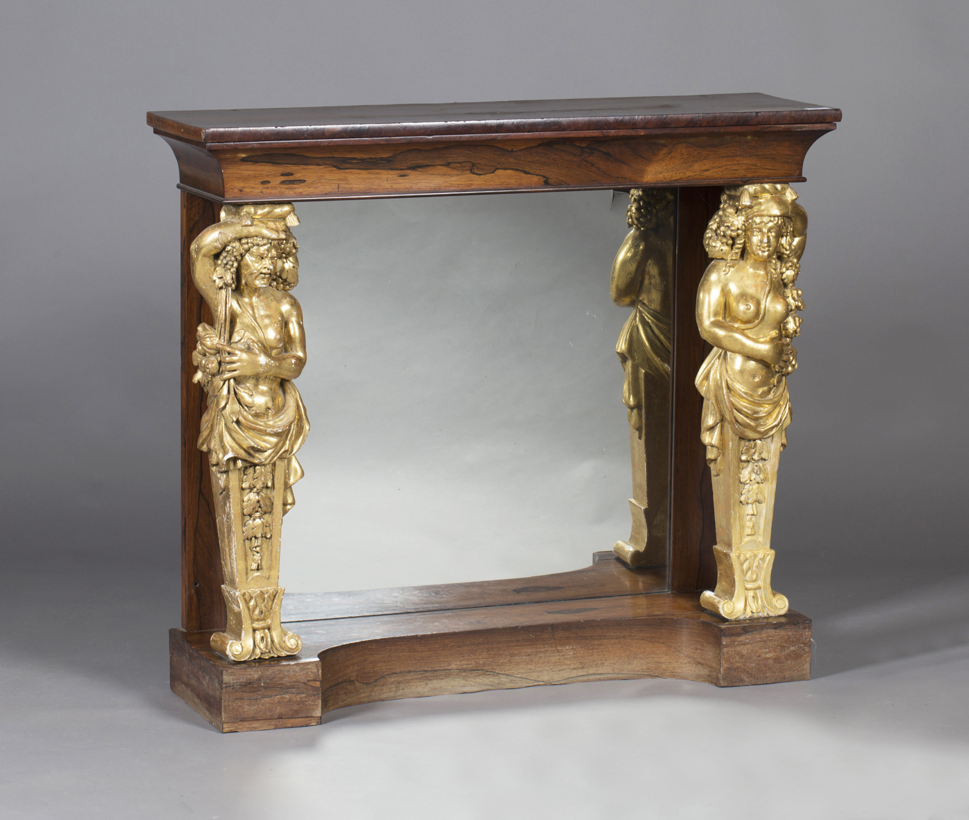 A Regency rosewood console table, the later veneered yew top supported by a pair of giltwood and